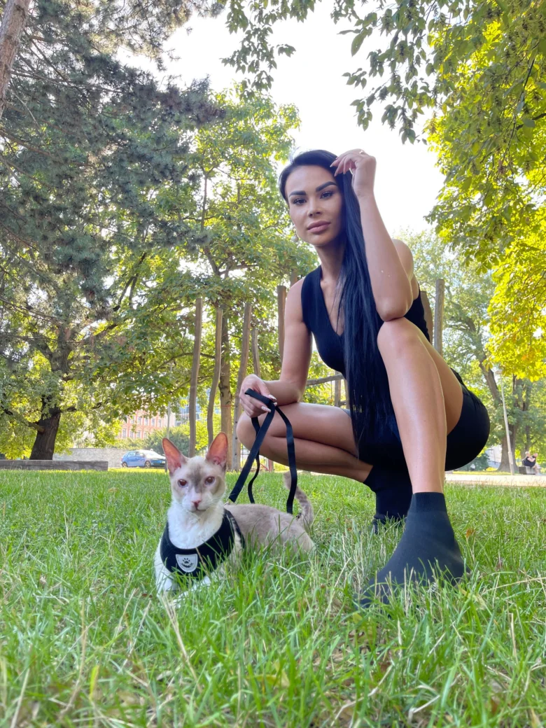 Žena s kočkou na vodítku v parcích