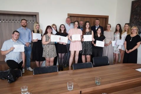 Skupina lidí držících certifikáty v interiéru.