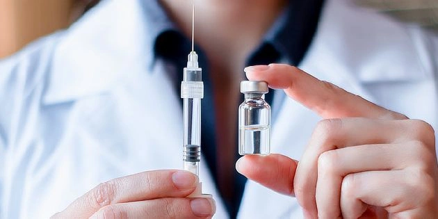 Lékař drží očkovací láhev a stříkačku pro obecný kontext.