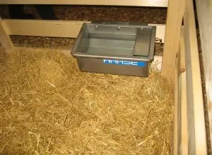 Vnitřek ovčího stáje s slámou a vodní nádrží.