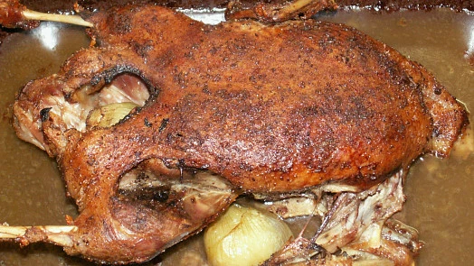Pečená kachna nebo husa v plechu s cibulí uvnitř.