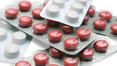 Červené a bílé tablety antibiotik v bublinkových obalech.