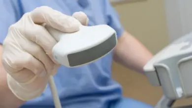 Rukou v rukavicích je drženo ultrazvukové sondu pro vyšetření prostaty.